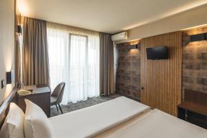 ソゾポルにあるKalithea Family Hotelのベッドとテレビが備わるホテルルームです。
