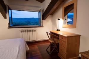 a bedroom with a desk and a large window at Posada La Olma in Polientes