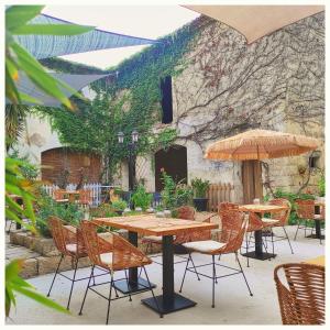 un patio con mesas, sillas y una sombrilla en La Vigneronne des Costières, en Vauvert