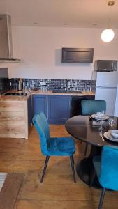 eine Küche mit einem Tisch und blauen Stühlen in der Unterkunft Chez germaine in Murat