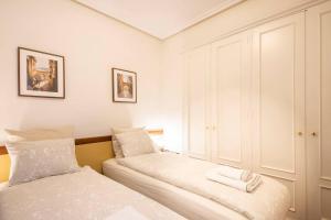 1 dormitorio con 2 camas con sábanas blancas en APARTAMENTO EN EL CORAZÓN DE LA CIUDAD con PARKING PRIVADO, en San Sebastián