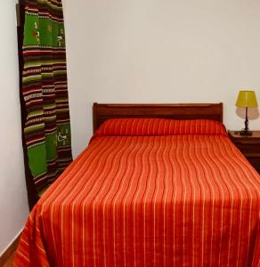 a bed with an orange striped comforter in a room at Casa rural Aloha Vera in Jarandilla de la Vera