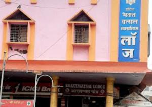 um edifício cor-de-rosa e amarelo com placas em Hotel Bhaktavatsal Tuljapur em Tuljapur