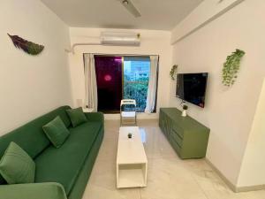 a living room with a green couch and a table at La Olive 1 BHK Service Apartment in Mumbai