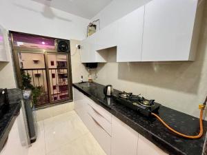 cocina con armarios blancos y encimera negra en La Olive 1 BHK Service Apartment, en Bombay