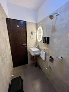W łazience znajduje się umywalka i lustro. w obiekcie La Olive 1 BHK Service Apartment w Bombaju