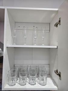 un armario lleno de vasos vacíos en un estante en LUXE Villa Near NEC, BHX & Train, en Birmingham