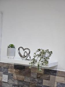 a white shelf with two metal hearts and plants at LUXE Villa Near NEC, BHX & Train in Birmingham