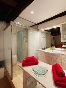 y baño grande con ducha y toallas rojas. en Grotto Flora B&B Chambres de charme, en Bigogno