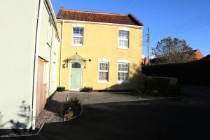a yellow house with a white door on a street at The Old Wagon & Horses 19th Century Beer House in Glastonbury