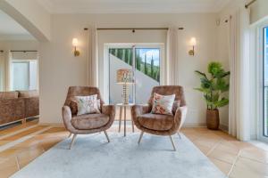 a living room with two chairs and a table at Villa Gasparini Palheiro Village by Holiday Rental Madeira in São Gonçalo +58 photos