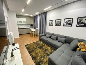 uma sala de estar com um sofá cinzento e uma cozinha em Arkle Apartment 6 em Tirana