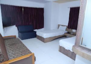 a hotel room with two beds and a window at Hotel Kewal INN Jalgaon in Jālgaon