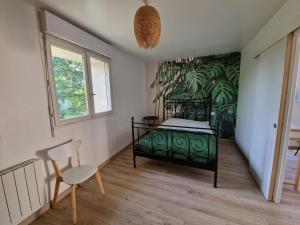 um quarto com uma cama verde e uma cadeira em La Source, location saisonnière proche Cognac em Saint-André