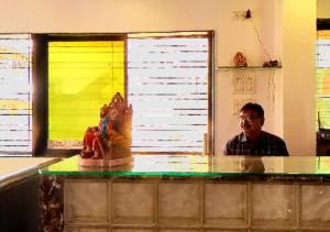 a man sitting at a counter in a kitchen at Hotel Kewal INN Jalgaon in Jālgaon