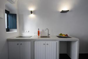 a white kitchen with a sink and a counter at Santorini traditional 1Bd apt with private hot tub in Fira