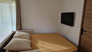 um pequeno quarto com uma cama e uma televisão de ecrã plano em Gîte Les Bruyères em Janville