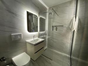 uma casa de banho branca com um lavatório e um espelho em Arkle Apartment 6 em Tirana