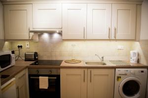 a kitchen with white cabinets and a sink at Exchange Suite Downtown in Dublin