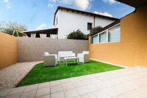 d'une terrasse avec des chaises blanches et de la pelouse. dans l'établissement Blue Island - Luxury House, à Olbia