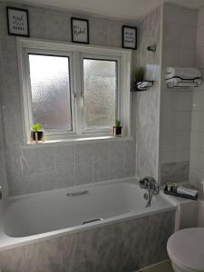ein Badezimmer mit einer Badewanne und einem WC sowie zwei Fenster in der Unterkunft Home in Beckton. Docklands. London City Airport. in London + 14 Fotos