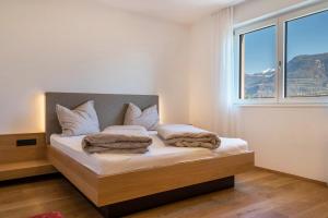 a bedroom with a bed with white sheets and a window at Ferienwohnungen Karin - Golden in Termeno