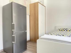 einen Kühlschrank aus Edelstahl in einem Zimmer mit einem Bett in der Unterkunft Pension 43 in Duisburg