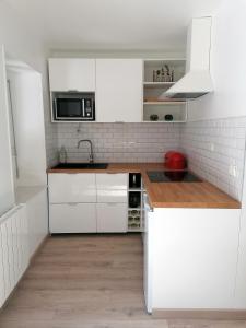 uma cozinha branca com armários brancos e um lavatório em La Source, location saisonnière proche Cognac em Saint-André