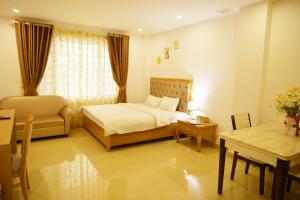 um quarto com uma cama, uma cadeira e uma mesa em GEM Apartment & Hotel em An Khê