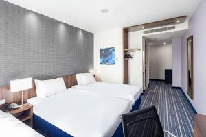 een hotelkamer met 2 bedden en een stoel bij Holiday Inn Express The Hague - Parliament by IHG in Den Haag +37 foto's