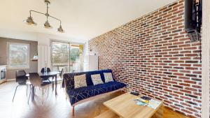 - un salon avec un mur en briques et un canapé bleu dans l'établissement HIPPODROME - Piscine - Parking Free - Métro, à Toulouse