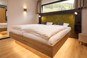 1 dormitorio con 1 cama grande y ventana grande en Siplinger Suites - Ferienwohnungen - Sauna und Fitness, en Balderschwang