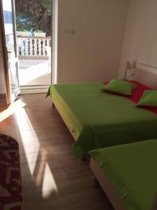 een slaapkamer met 2 groene bedden en een glazen schuifdeur bij Apartments Dobrana in Novalja