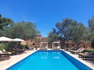 una piscina con tumbonas y sombrillas en Boutique Hotel Sa Galera, en Cas Concos