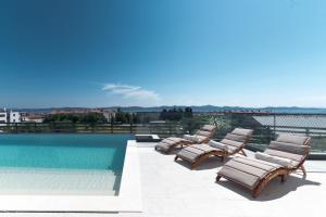 a group of lounge chairs next to a swimming pool at Villa Aurum ZadarVillas in Zadar
