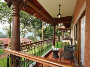 un portico di una casa con sedie e un tavolo di Tapovana The Fern Heritage Resort, Sakleshpur a Sakleshpur