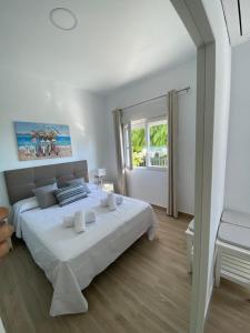 een witte slaapkamer met een groot bed en een raam bij Sea Escape in Almuñécar