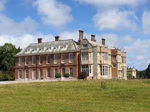 a large brick building on a grass field at Tree Top View Sheringham - Reverse Living - EV Charger - Quirky in Sheringham