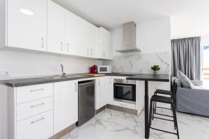 a kitchen with white cabinets and a black counter top at Home2Book Bright Studio Ocean View Tabaiba in Tabaiba