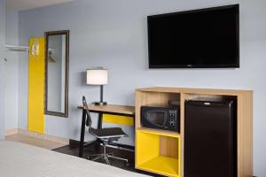 a hotel room with a desk with a television and a bed at Days Inn by Wyndham Queensbury/Lake George in Queensbury