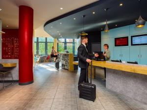 a man in a suit standing at a counter with a suitcase at ibis Luzern Kriens in Lucerne
