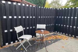 two chairs and a table in front of a fence at My Loft by Esen Hamburg Netflix, Parkplatz, Terasse in Hamburg