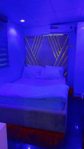 a bed in a room with a blue light at HOUSE 27 HABITAT in Lagos