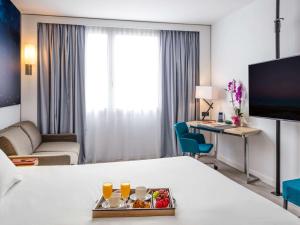 ein Hotelzimmer mit einem Bett und einem Schreibtisch mit einem Tablett mit Speisen in der Unterkunft Novotel Barcelona Cornellà in Cornellà de Llobregat