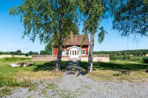 une maison rouge avec deux arbres devant elle dans l'établissement Gård med egen sjö med bryggbåt, nyrenoverat!, à Katrineholm