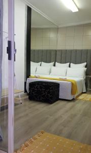 uma cama grande com almofadas brancas num quarto em The Link on Elgin em Kempton Park
