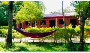 a red house with a red hammock in a yard at Kandalama Hostel in Dambulla