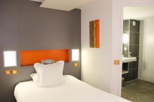 een slaapkamer met een wit bed en een badkamer bij Hôtel Best Western The Wish Versailles in Guyancourt