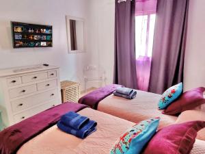 コラレホにあるAmore e Magia Corralejoのツインベッド2台(紫のシーツ付)が備わるベッドルーム1室