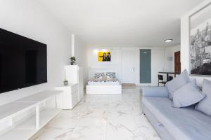 a white living room with a couch and a tv at Home2Book Bright Studio Ocean View Tabaiba in Tabaiba